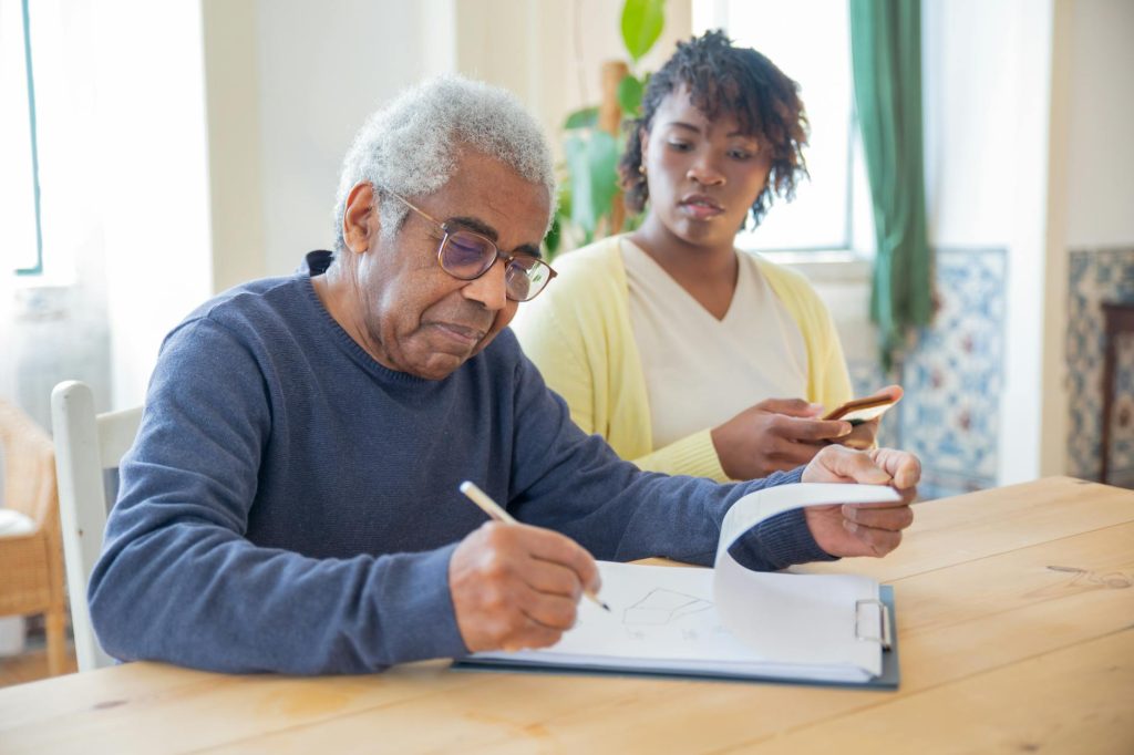a man in blue sweater holding a pen and writing on a white paper